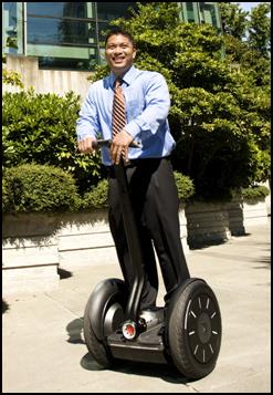 A man in business attire using a Segway.